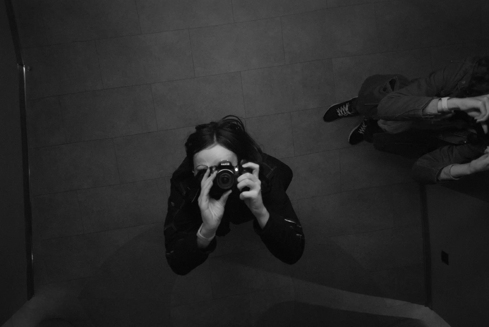 black and white photo of me pointing my dslr at a mirror in the ceiling.
