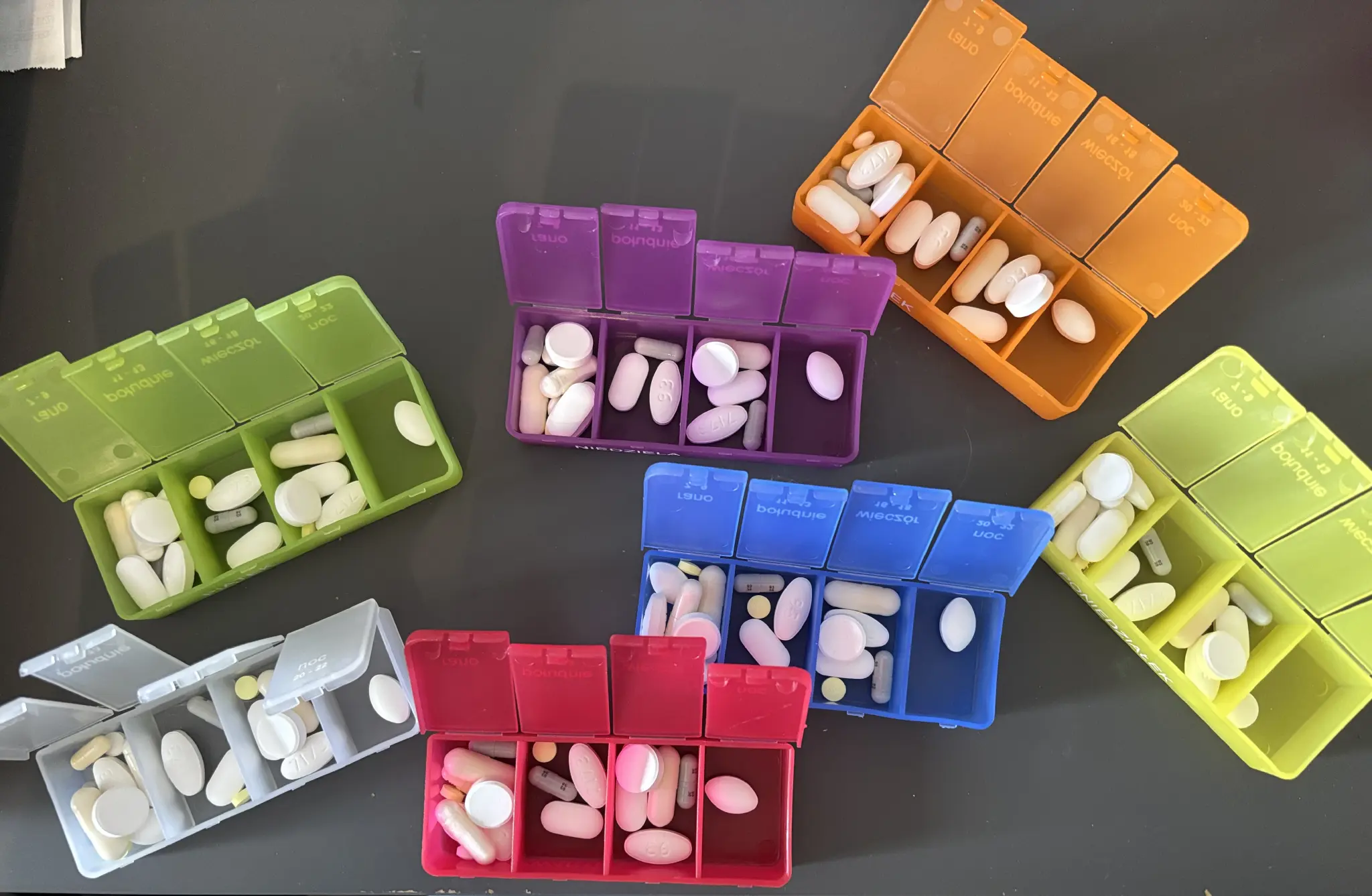 7 colourful medication organisers, filled with 18-19  pills per day