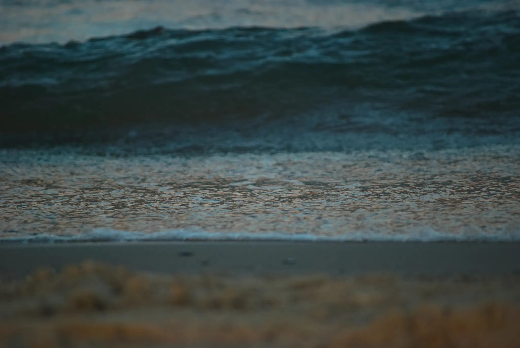 the same, except the remains of a wave flowing back into the ocean are in focus, and there's a big wave in the background that's about to crash.