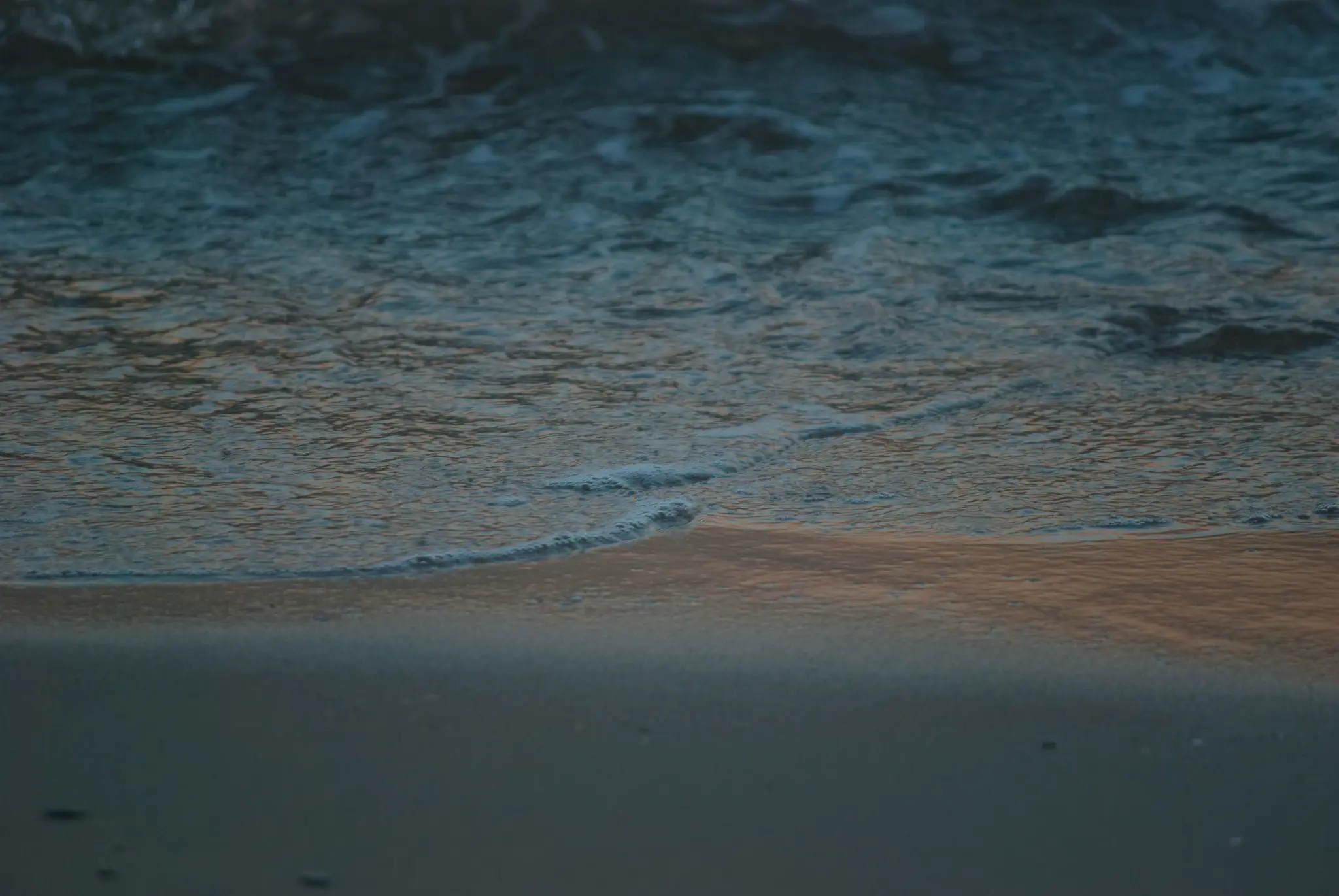 a much calmer shot of the same scene. the incoming wave is still a moment from crashing, and there's a nice gradient from the orange of the reflected sunset into the deep turquoise of the ocean wave.