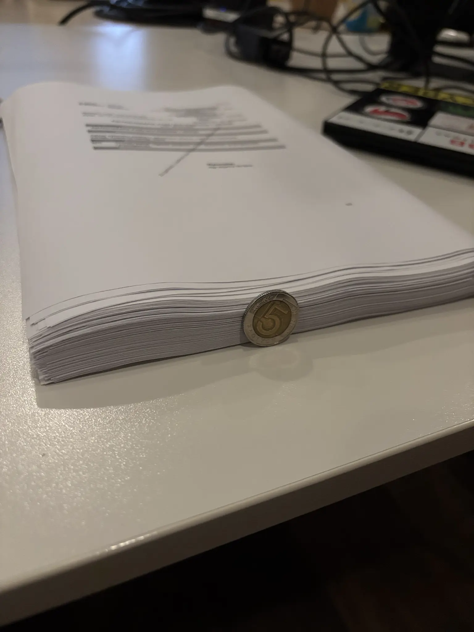 a stack of 176 pages of paper. a 5pln coin is placed on its side and the paper stack is about as tall as the 5pln coin is wide