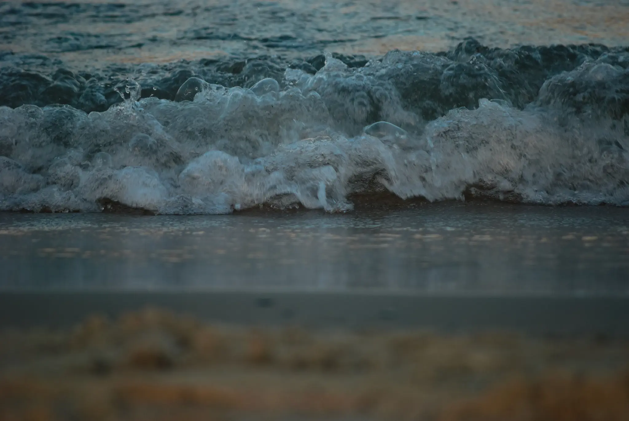 the same kind of scene photographed from an even lower angle, making the crashing wave the only thing that's actually in focus, with the beach in the foreground and the ocean in the background both being blurry.